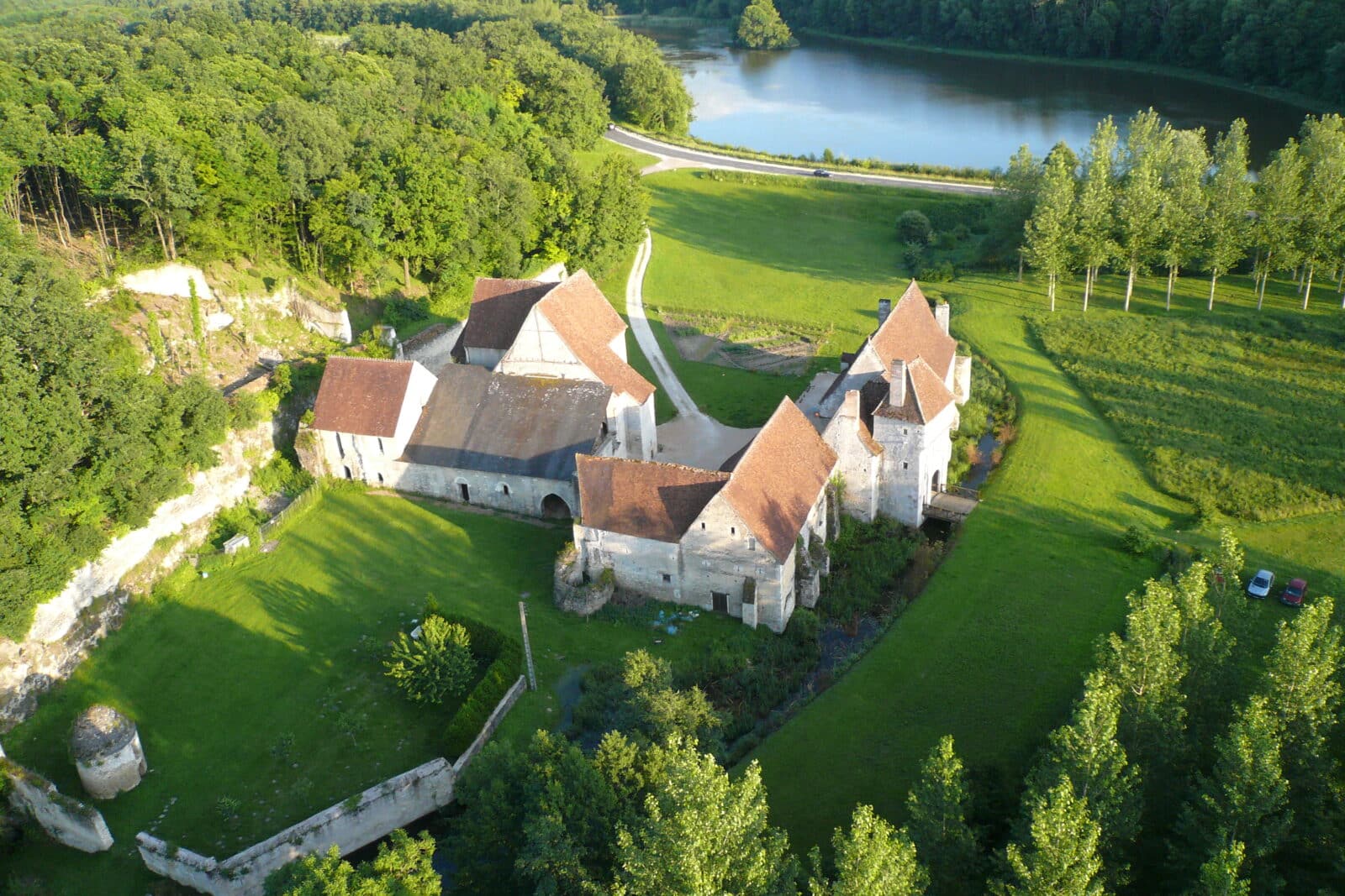 Vue aérienne du château-monastère de la Corroirie, niché entre forêt et étangs, avec accès direct par la route de Loches à Montrésor (RD 760), à 4 km de Montrésor et 12 km de Loches